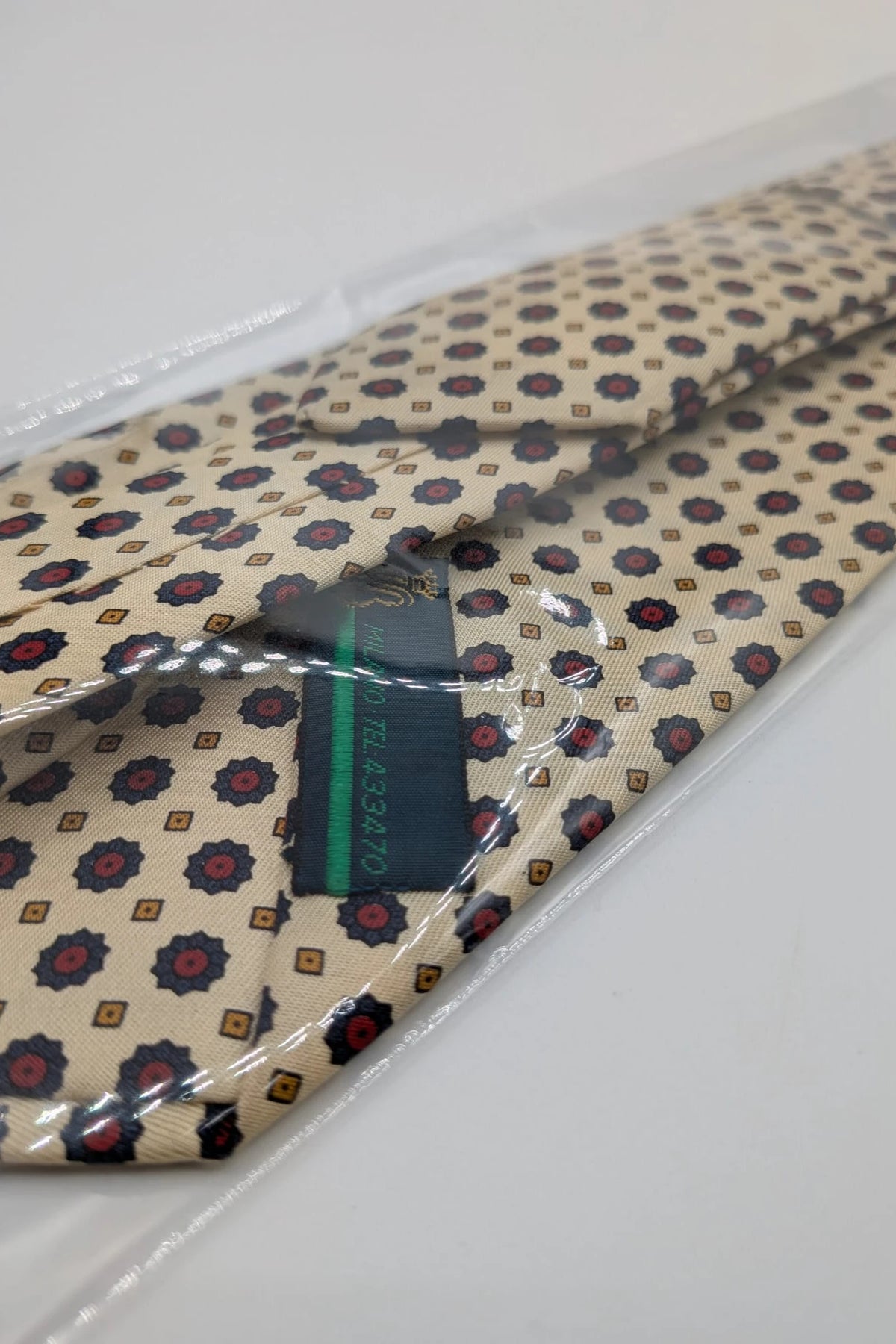Uomo beige tie with floral pattern, blue and red flowers, geometric ochre details.