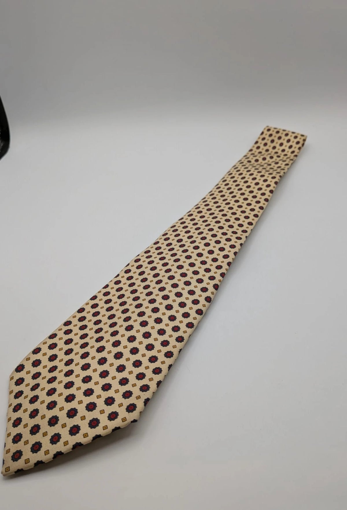 Uomo beige tie with floral pattern, blue and red flowers, geometric ochre details.